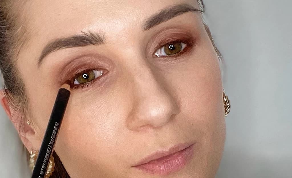 Frau schminkt sich mir Kajal Smokey Eyes