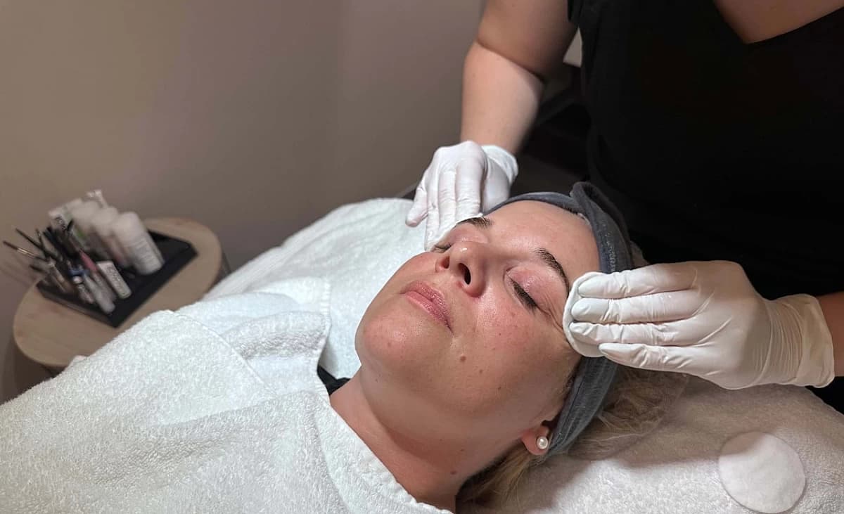 Der Kundin wird mit Wattepads Toner aufs Gesicht aufgetragen.