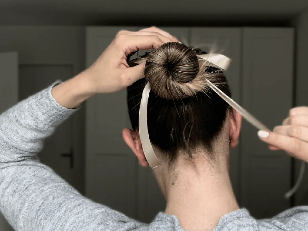 Frau bindet Schleife um ihren Dutt für den trendy Ballet Core Look