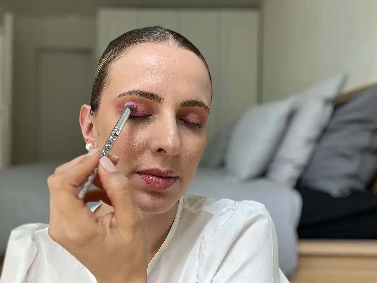 Frau verteilt pinken Lidschatten auf dem Oberlid
