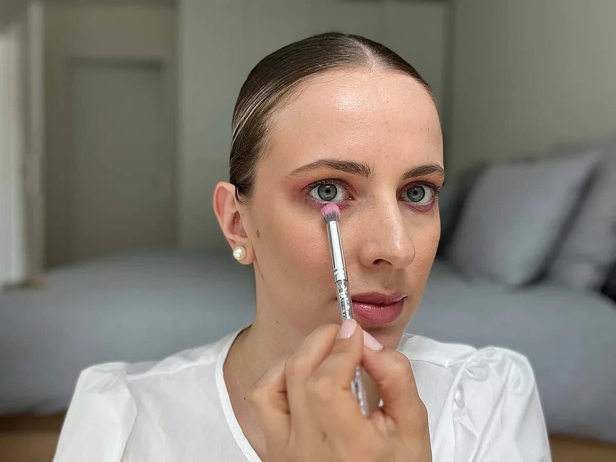 Frau verteilt pinkenLidschatten unter dem Auge