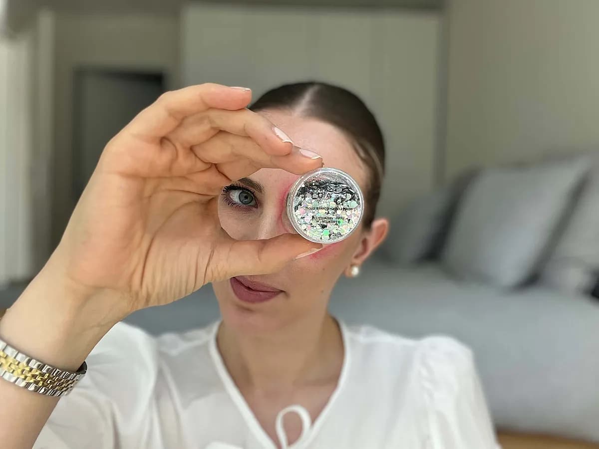 Frau zeigt Glitzerlidschatten von VBEAUTY