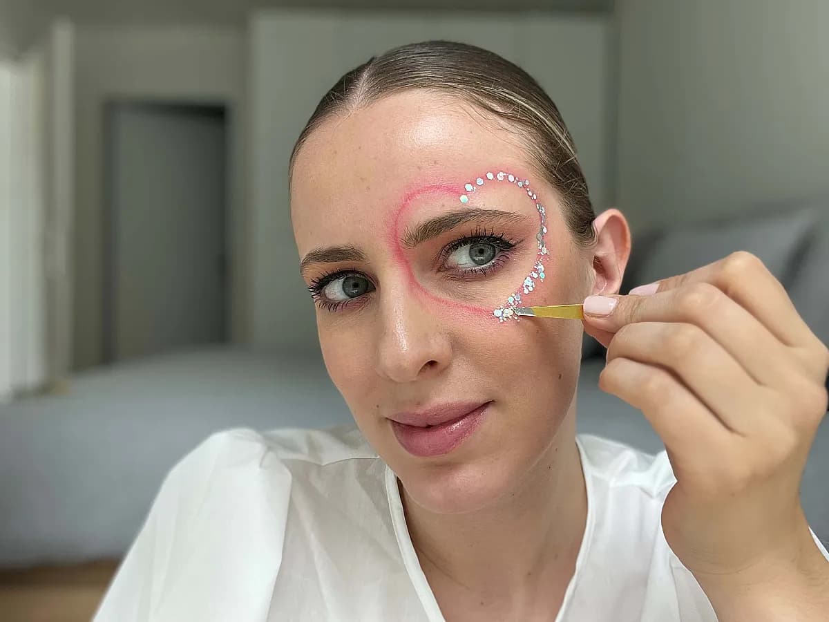 Frau setzt Glitterpartikel aufs Gesicht