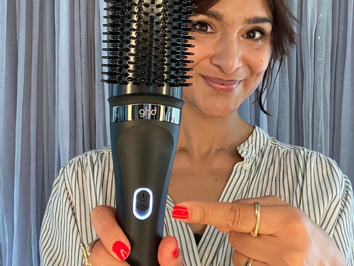 Frau zeigt auf den Bedinungsknopf der ghd Duet Blowdry Brush